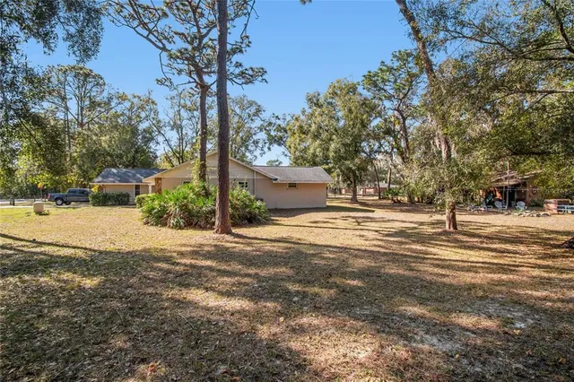 a view of a house with a yard and large trees