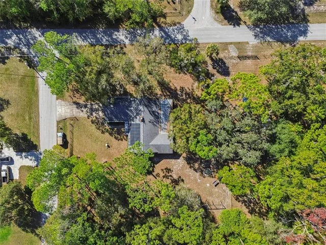 a view of a big house in front of a yard with plants and large trees