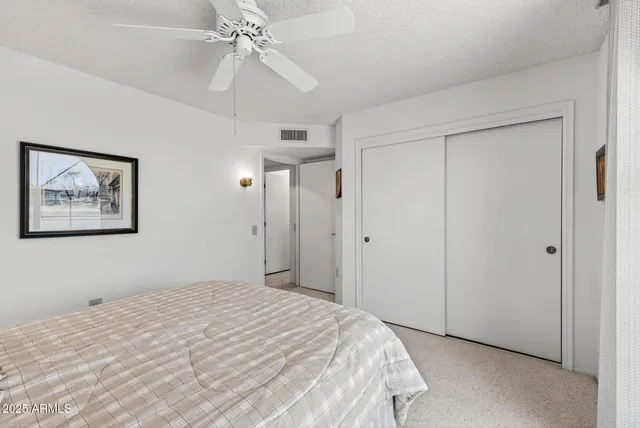 a bedroom with a large bed and a chandelier fan