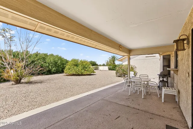 a patio with a table and chairs and potted plants