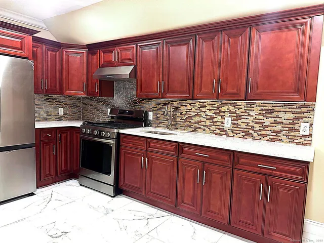 a kitchen with granite countertop wooden cabinets a sink and a stove