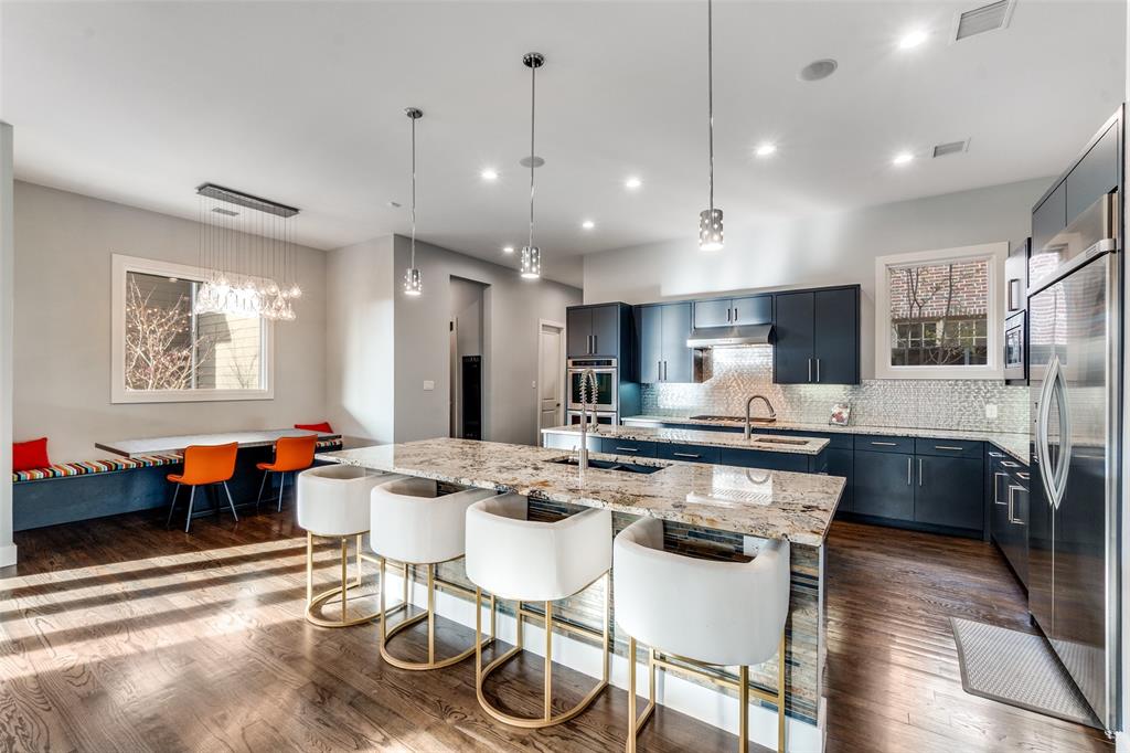 7912 Hanover Street Dallas, TX 75225 - Photo 21 of 29 Spacious kitchen featuring dark cabinetry, stainless steel appliances, a large center island with a granite countertop, and wood-finish flooring throughout