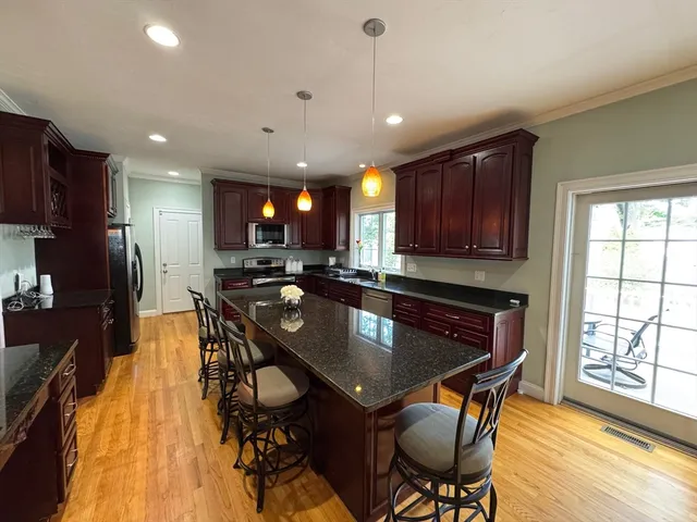 a kitchen with stainless steel appliances granite countertop a stove a refrigerator a sink a stove a dining table and chairs with wooden floor