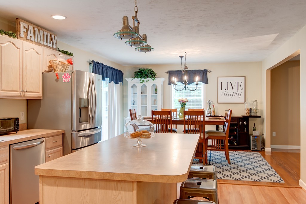 6 Vinton Road Sturbridge, MA 01566 - Photo 7 of 20 a large kitchen with kitchen island a refrigerator a stove a dining table and chairs with wooden floor