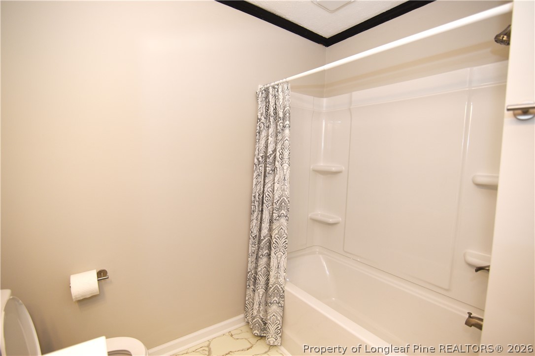 1673 Norment Road Lumberton, NC 28360 - Photo 29 of 32 a bathroom with a shower curtain and a toilet