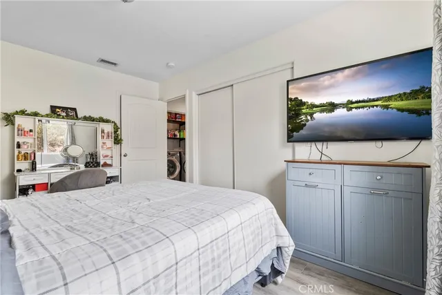a bedroom with a bed and a flat tv screen on dresser