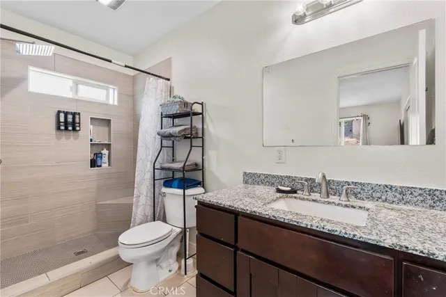 a bathroom with a granite countertop sink a toilet and shower