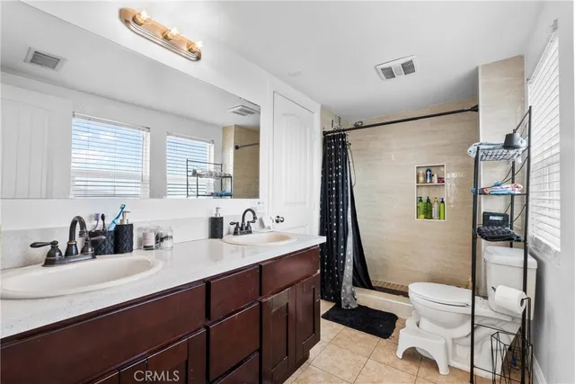 a bathroom with a double vanity sink toilet mirror and shower