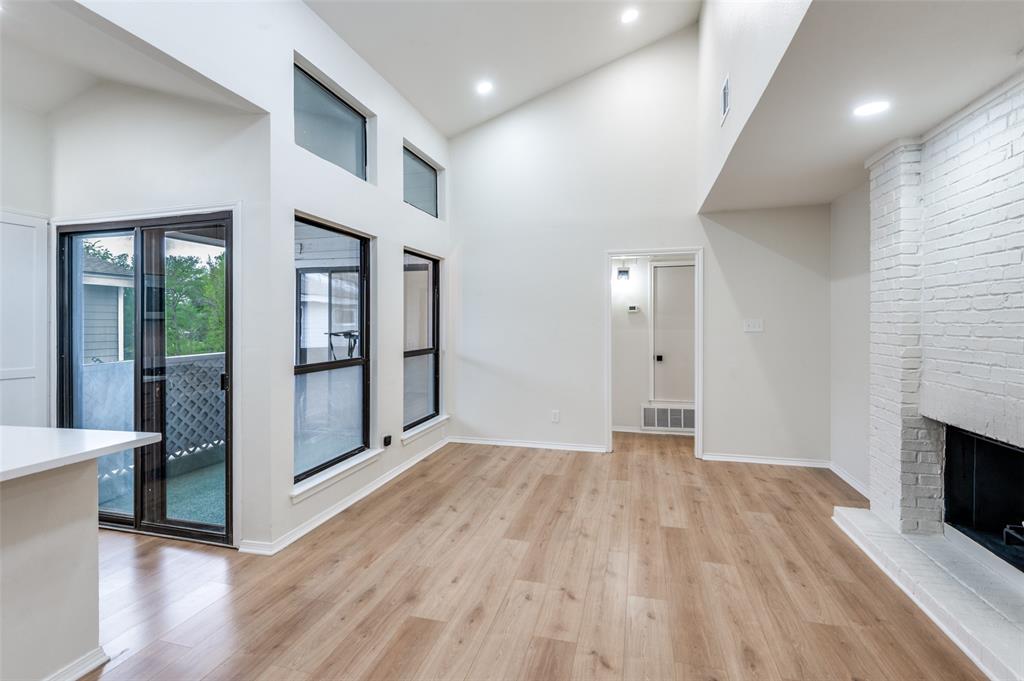 17490 Meandering Way, Unit 2202 Dallas, TX 75252 - Photo 7 of 24 Spacious living area featuring high vaulted ceilings, wood-finish flooring, a painted brick fireplace, and multiple windows