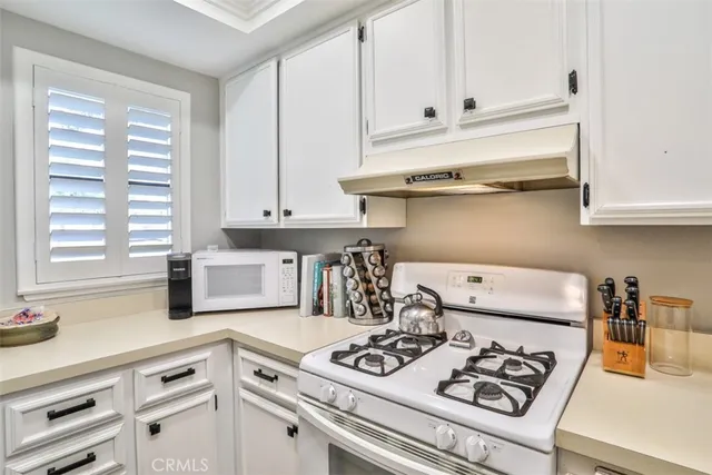 a kitchen with white cabinets and white appliances