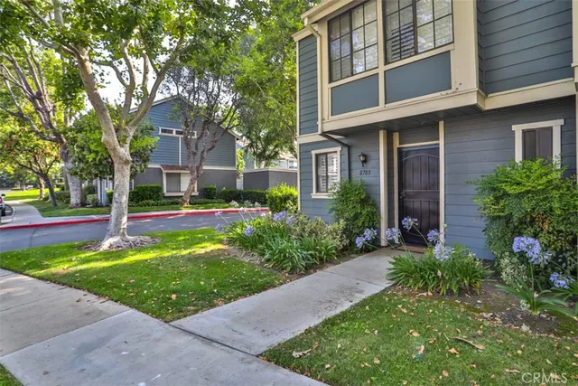a view of a brick house with a yard and plants