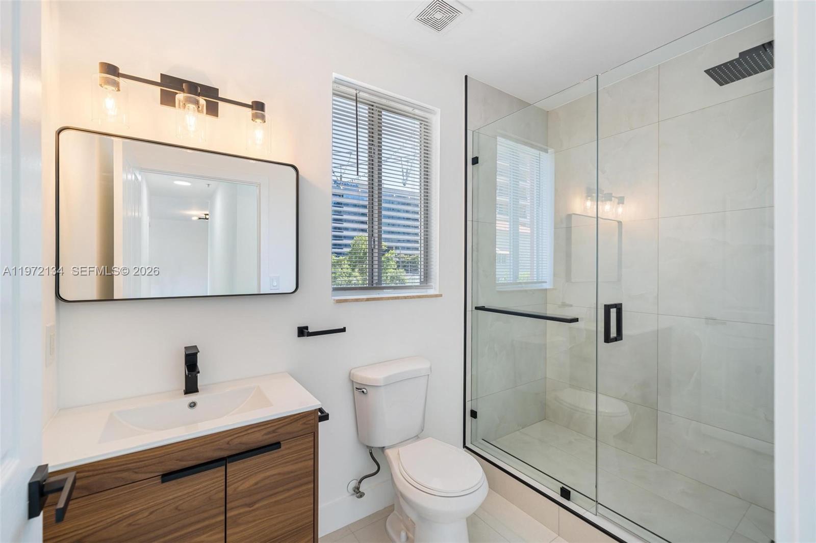 2280 Southwest 32nd Avenue, Unit 201 Miami, FL 33145 - Photo 9 of 23 a bathroom with a toilet a sink a mirror and vanity