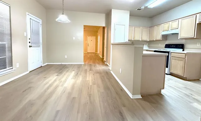 a kitchen with granite countertop a refrigerator a sink dishwasher a stove and white cabinets with wooden floor