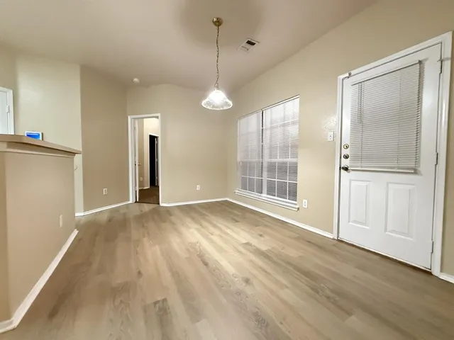 an empty room with wooden floor cabinet and windows