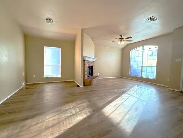 an empty room with windows and a fireplace