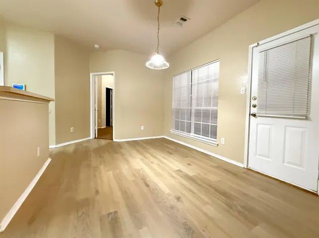 a view of an empty room with glass door and wooden floor