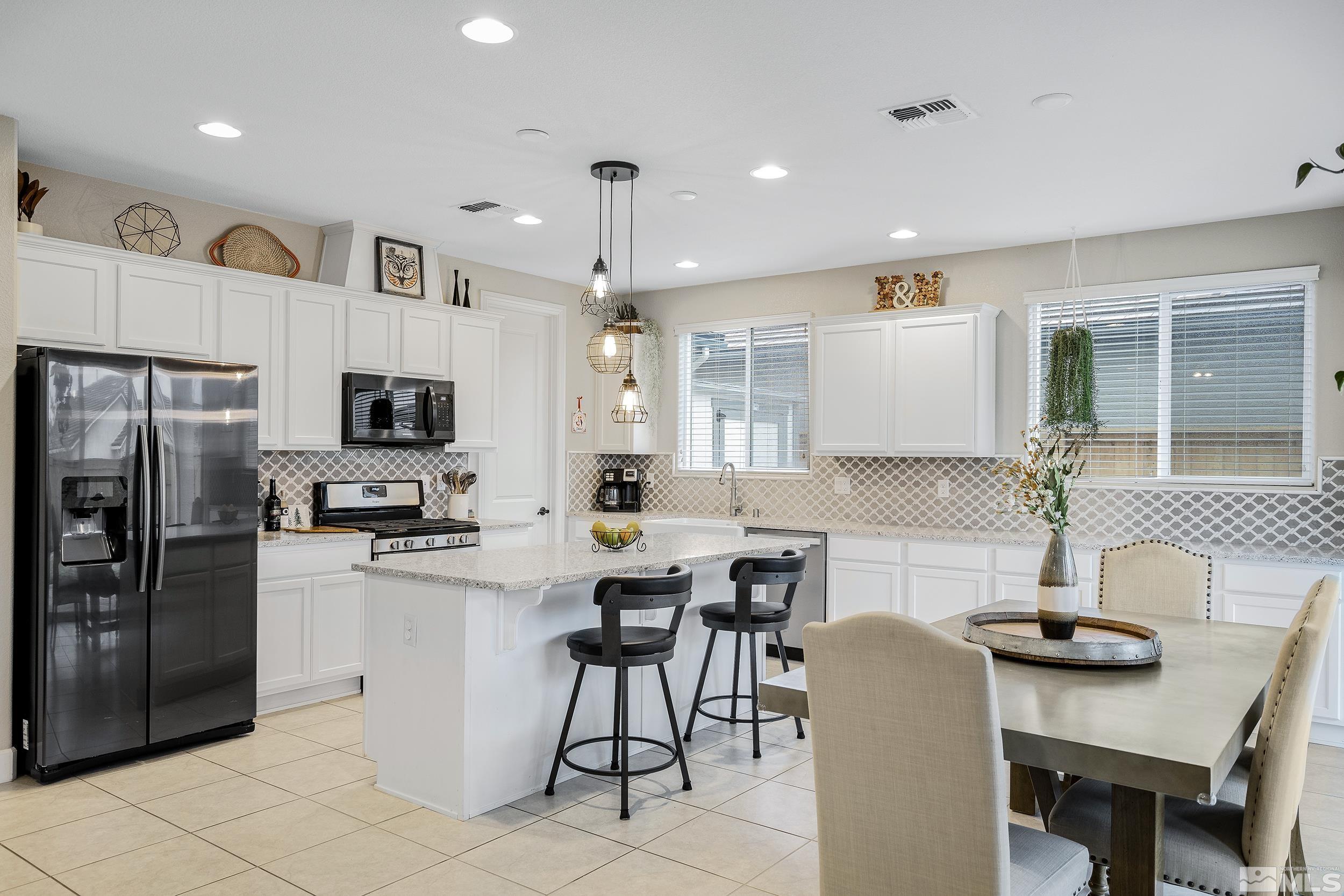 3300 Show Jumper Lane Reno, NV 89521 - Photo 14 of 40 a kitchen with stainless steel appliances kitchen island granite countertop a refrigerator a stove a sink a dining table and chairs