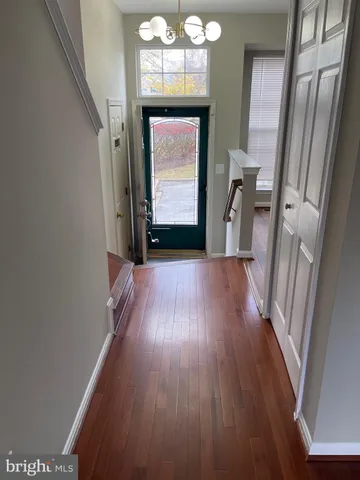 a view of a hallway with wooden floor and a chandelier