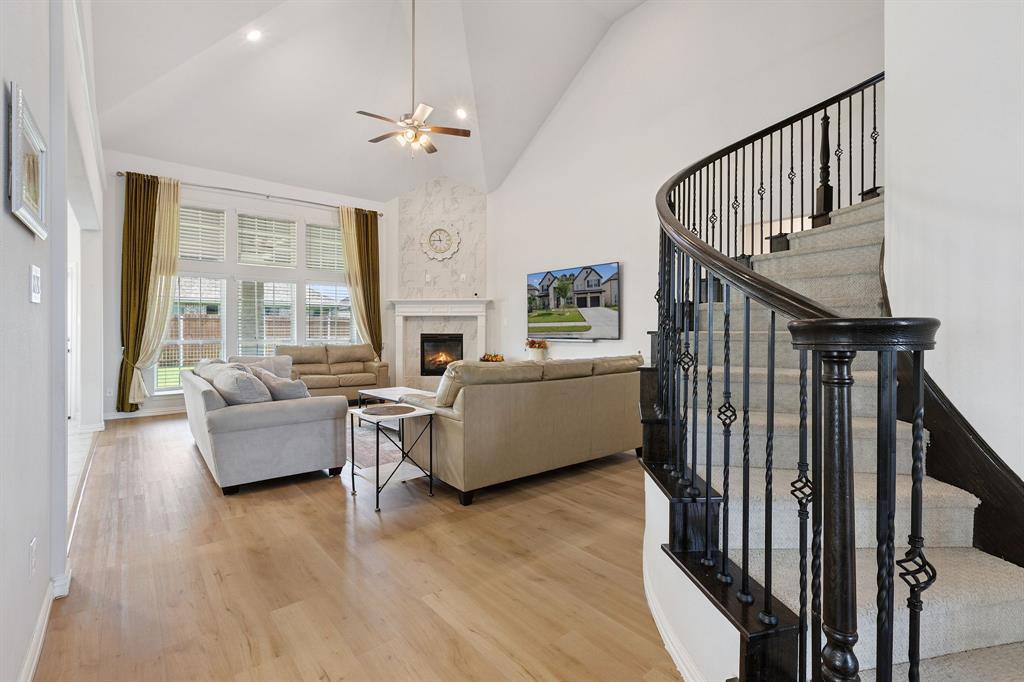 Undisclosed Address Wylie, TX 75098 - Photo 6 of 26 Living area with high vaulted ceiling, light wood-style floors, a ceiling fan, stairs, and a fireplace
