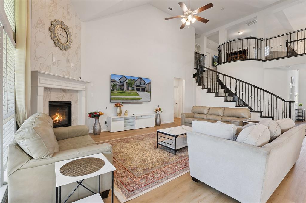 Undisclosed Address Wylie, TX 75098 - Photo 7 of 26 Living area with stairway, wood like finished floors, a ceiling fan, and high vaulted ceiling