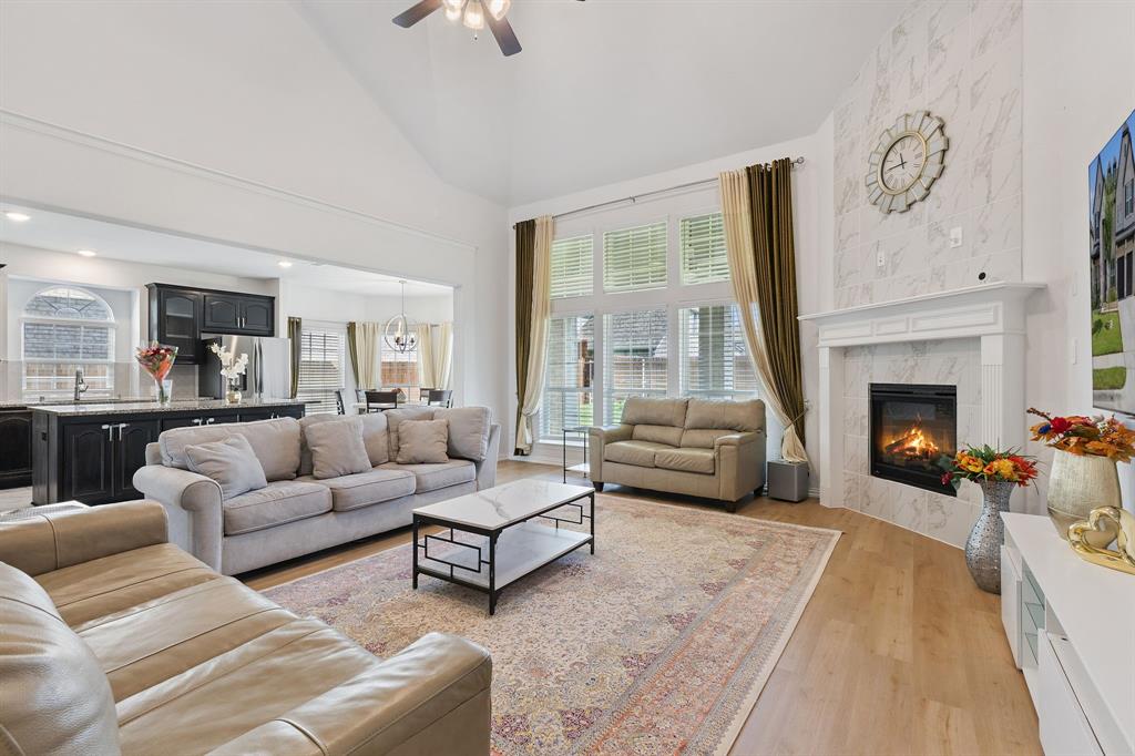 Undisclosed Address Wylie, TX 75098 - Photo 8 of 26 Living room featuring light wood finished floors, a fireplace, ceiling fan, high vaulted ceiling, and a chandelier