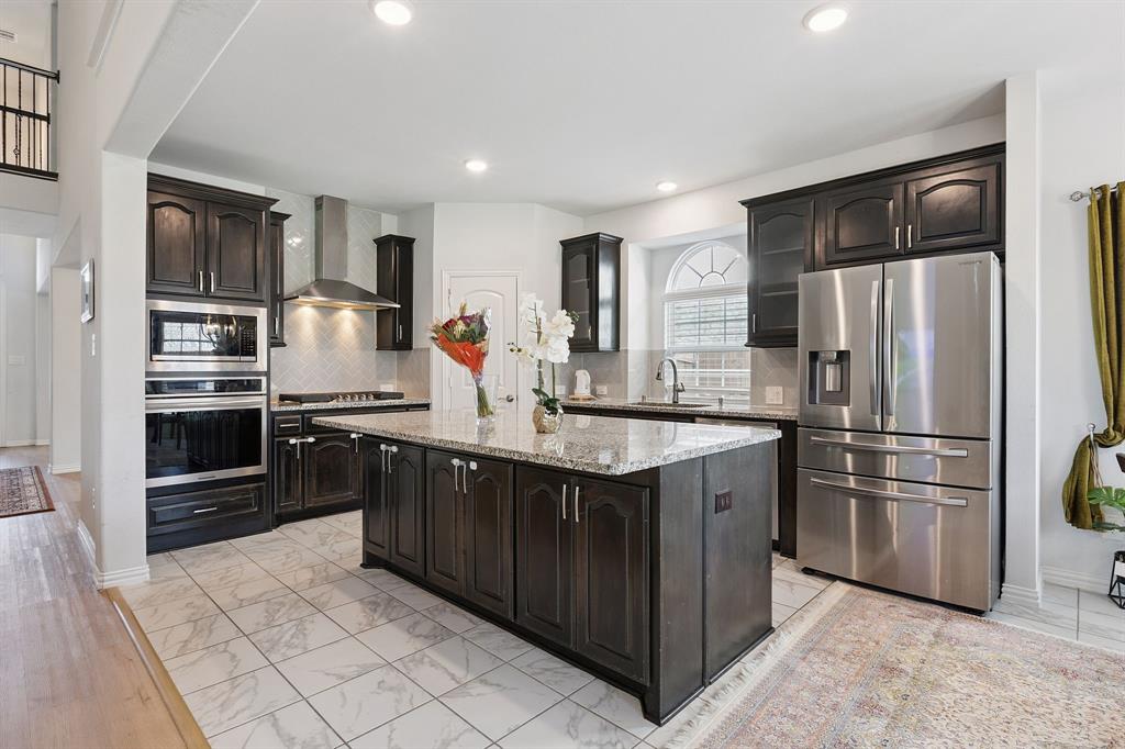 Undisclosed Address Wylie, TX 75098 - Photo 9 of 26 Kitchen with stainless steel appliances, tasteful backsplash, a center island, wall chimney range hood, and recessed lighting