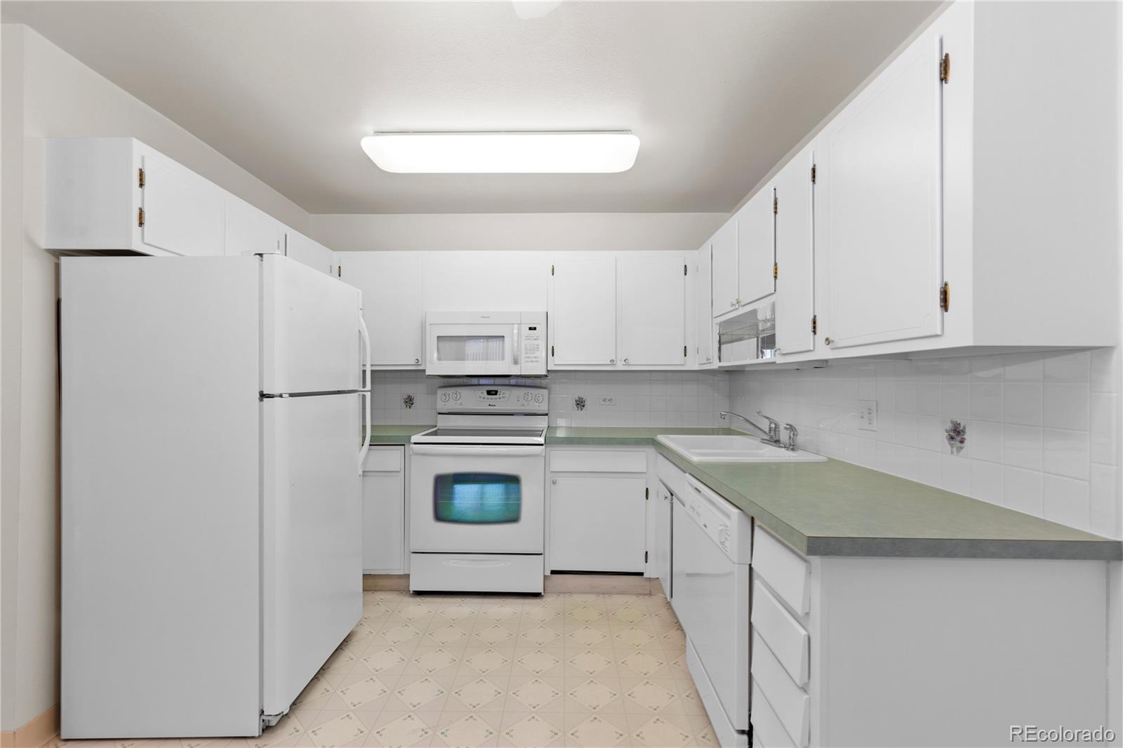 750 South Clinton Street, Unit 2B Denver, CO 80247 - Photo 12 of 43 a kitchen with a sink a refrigerator and cabinets