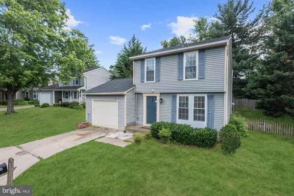 a view of a house with a yard plants and large tree