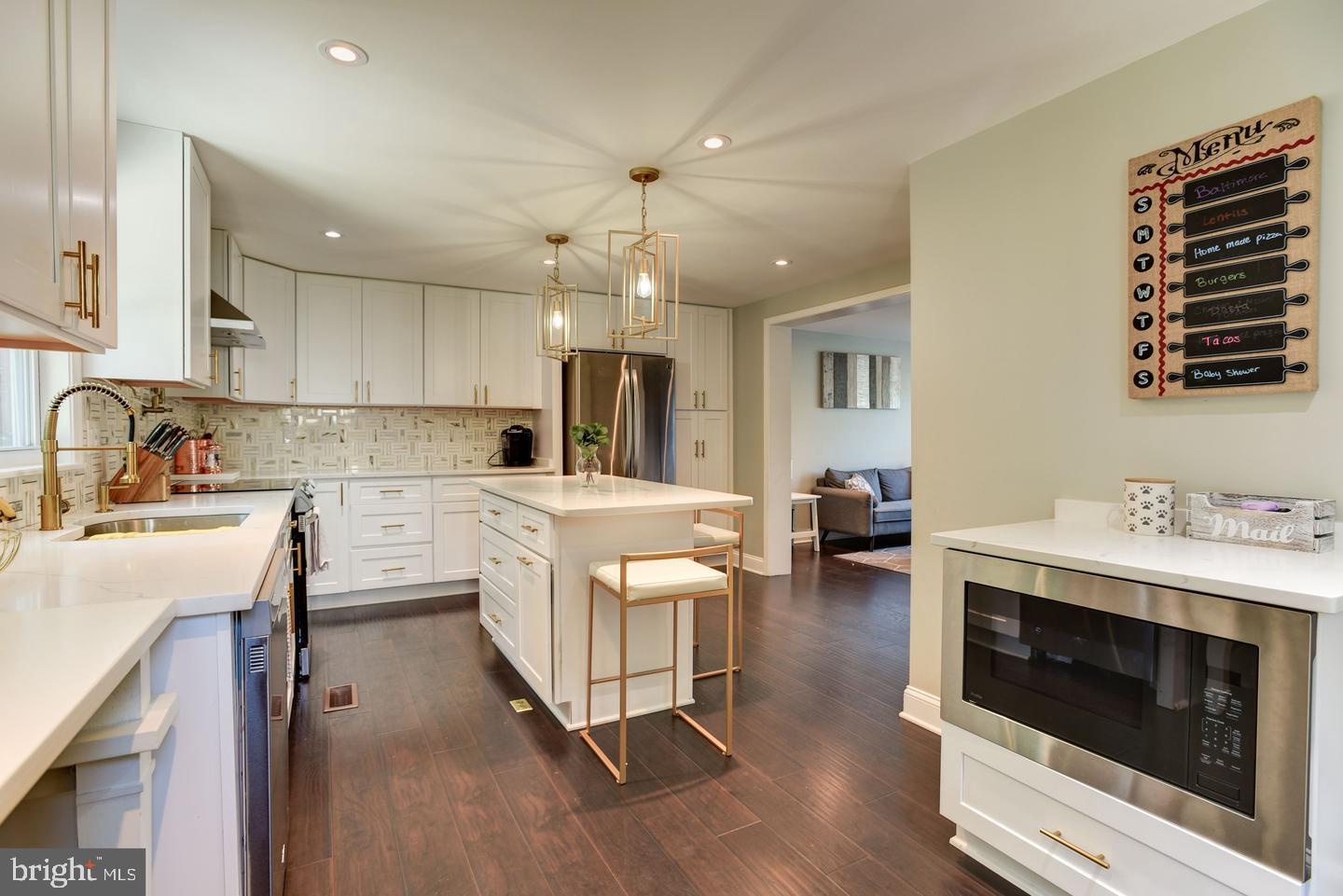 7310 Torran Rocks Way Gaithersburg, MD 20879 - Photo 10 of 32 a kitchen with stainless steel appliances kitchen island granite countertop a sink cabinets and wooden floor