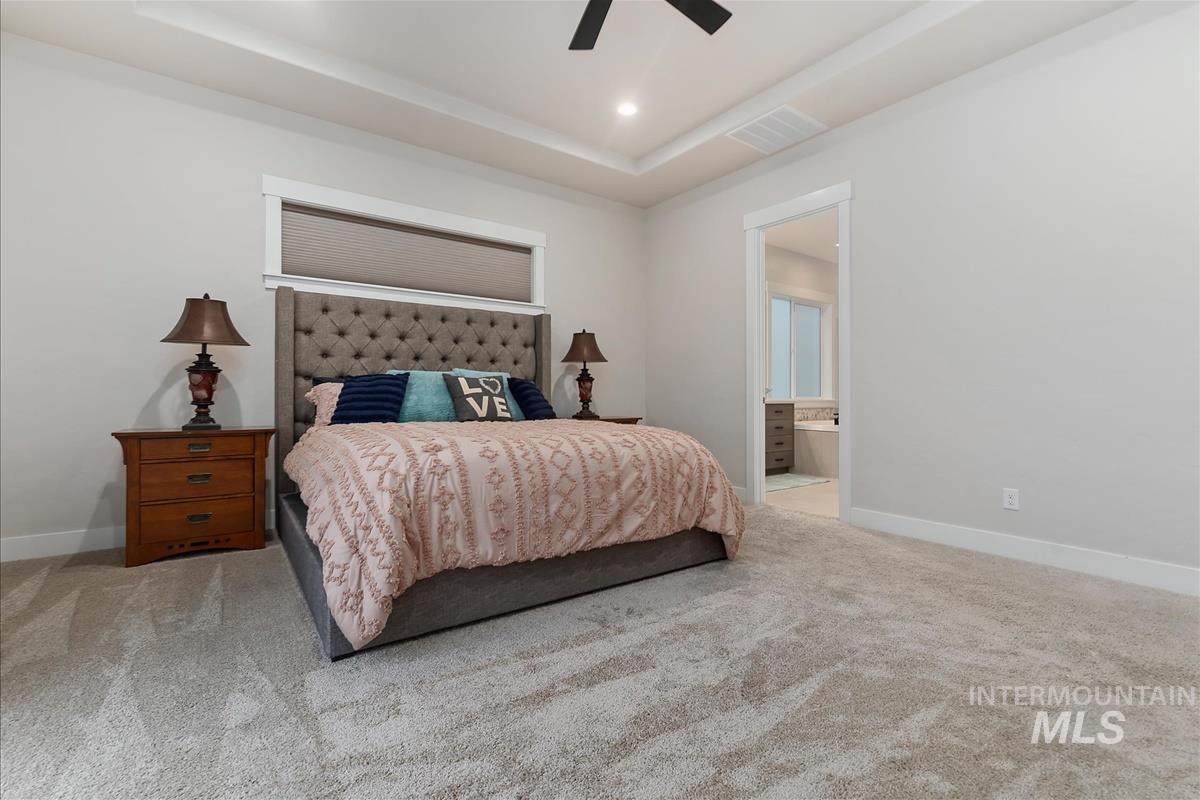 3413 North Hosta Avenue Star, ID 83669 - Photo 14 of 50 Bedroom featuring a raised ceiling, light colored carpet, ensuite bath, a ceiling fan, and recessed lighting