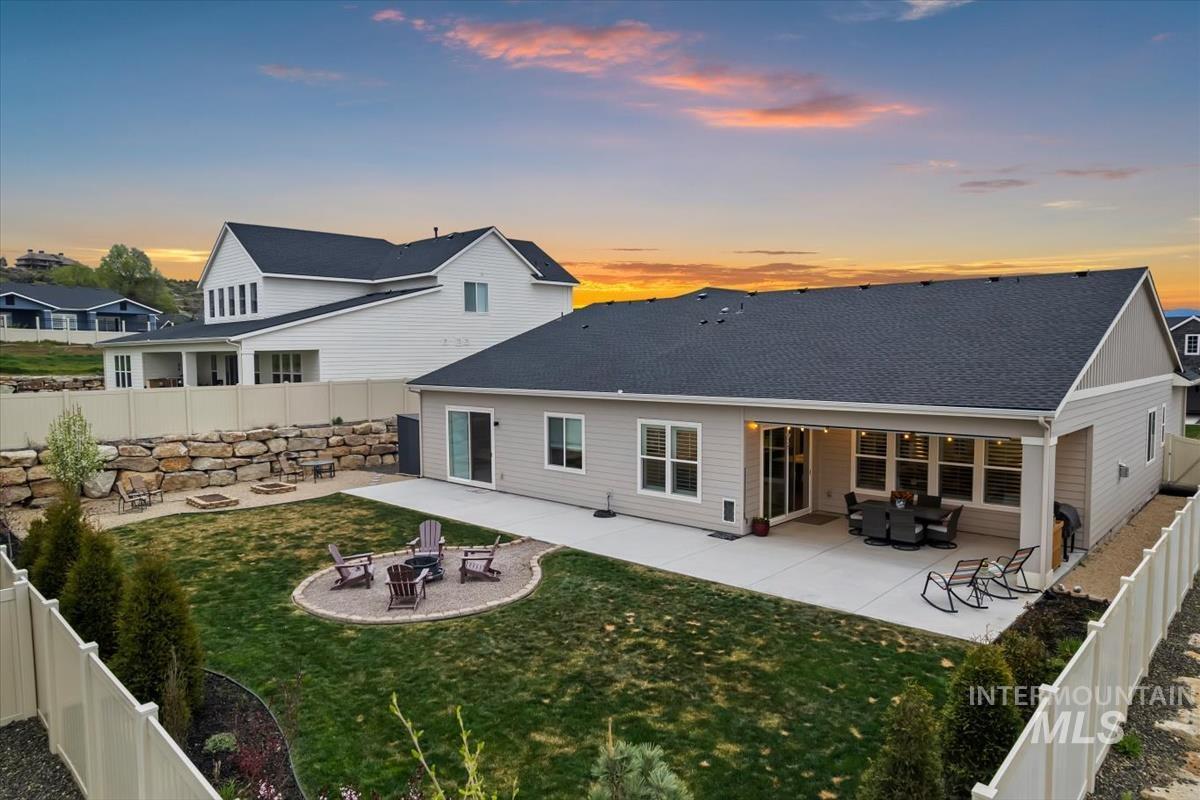 3413 North Hosta Avenue Star, ID 83669 - Photo 37 of 50 Back of house at dusk featuring a fire pit, a fenced backyard, a patio, and a shingled roof