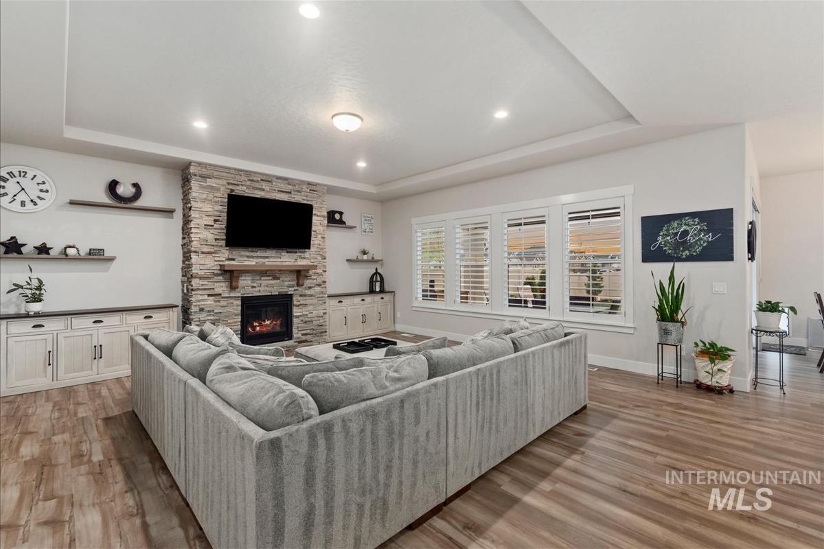 3413 North Hosta Avenue Star, ID 83669 - Photo 4 of 50 Living area featuring a tray ceiling, light wood-style floors, a stone fireplace, and recessed lighting