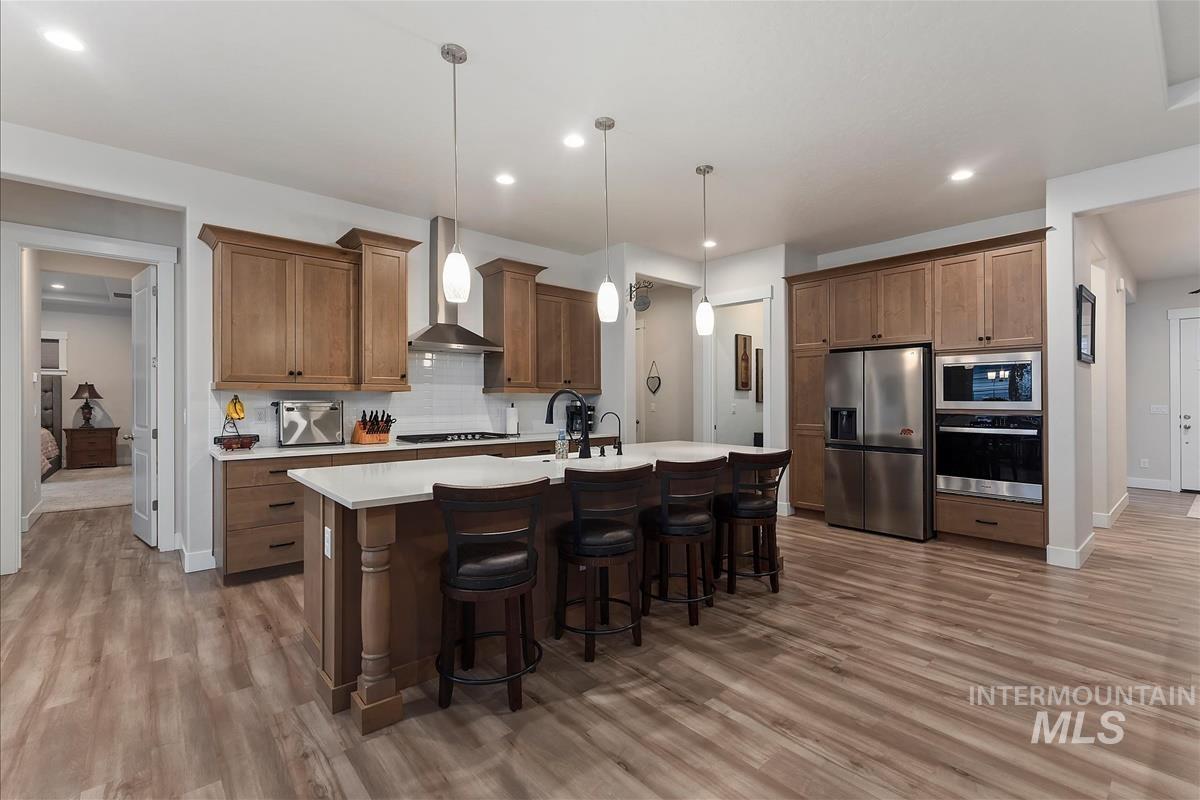 3413 North Hosta Avenue Star, ID 83669 - Photo 7 of 50 Kitchen featuring stainless steel appliances, a kitchen breakfast bar, hanging light fixtures, decorative backsplash, and a kitchen island with sink
