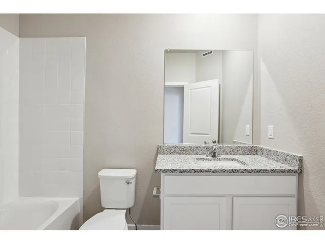 a bathroom with a granite countertop sink a toilet and a mirror