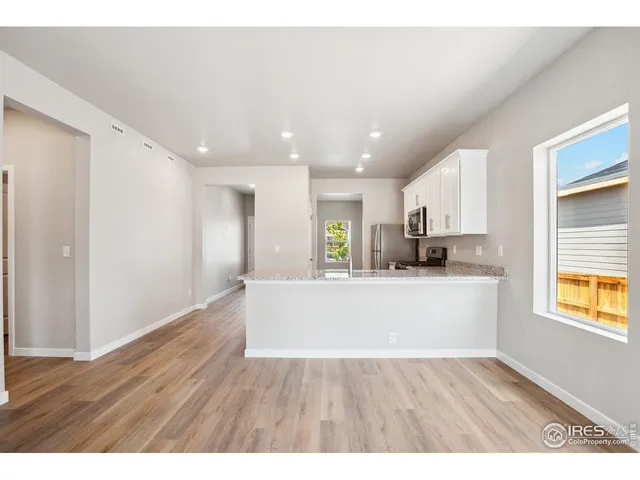 a view of kitchen with stainless steel appliances granite countertop a refrigerator a sink a stove and wooden floor