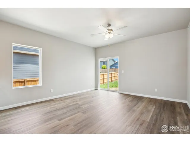 a view of an empty room with window and wooden floor