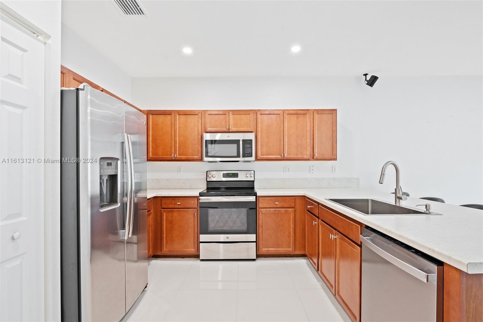 9361 West 33rd Way Hialeah, FL 33018 - Photo 8 of 30 a kitchen with stainless steel appliances granite countertop a sink stove and refrigerator
