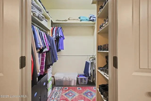 a view of walk in closet with clothes and shoes