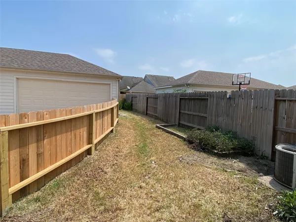 a view of a backyard with plants and wooden fence