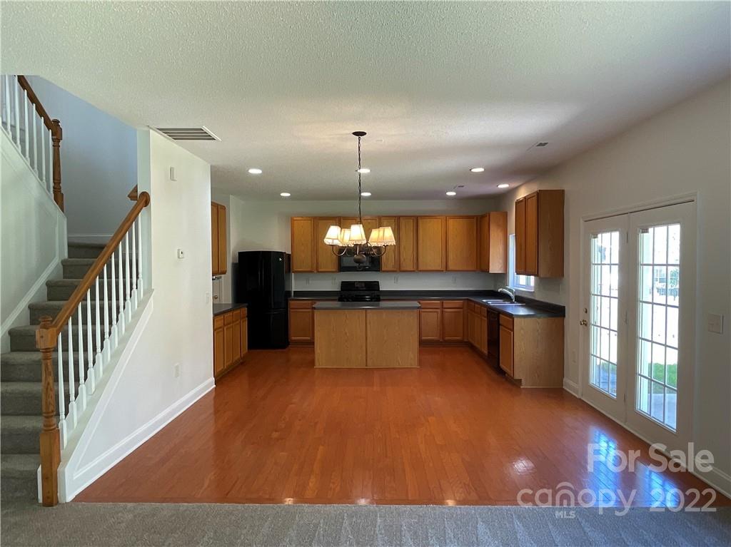 13712 Rutherglen Court Charlotte, NC 28213 - Photo 6 of 22 a open kitchen with stainless steel appliances kitchen island granite countertop a refrigerator a stove and a sink with wooden floor