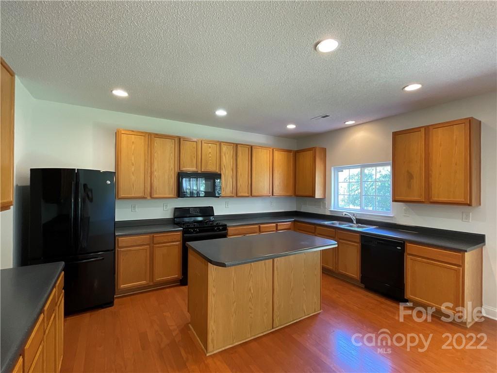 13712 Rutherglen Court Charlotte, NC 28213 - Photo 8 of 22 a kitchen with granite countertop stainless steel appliances a refrigerator a sink a stove a counter space and cabinets