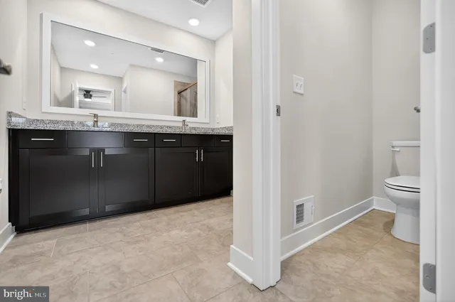 a bathroom with a granite countertop sink a toilet and a mirror