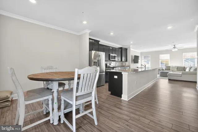 a kitchen with stainless steel appliances kitchen island granite countertop a table chairs sink and cabinets