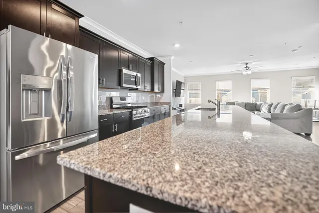 a large kitchen with kitchen island a large counter top stainless steel appliances and cabinets