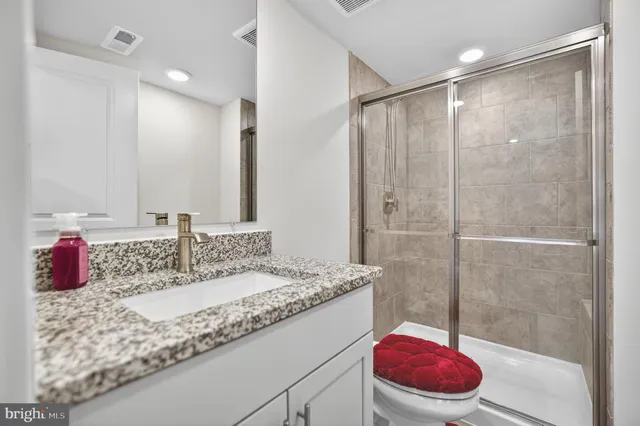 a bathroom with a granite countertop sink a toilet and shower