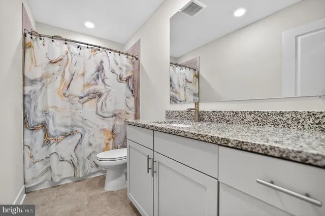 a bathroom with a granite countertop sink and a mirror