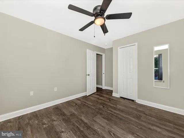 an empty room with wooden floor ceiling fan and windows