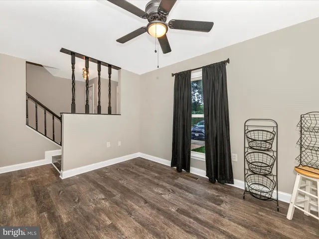 a view of an empty room with window and hardwood floor