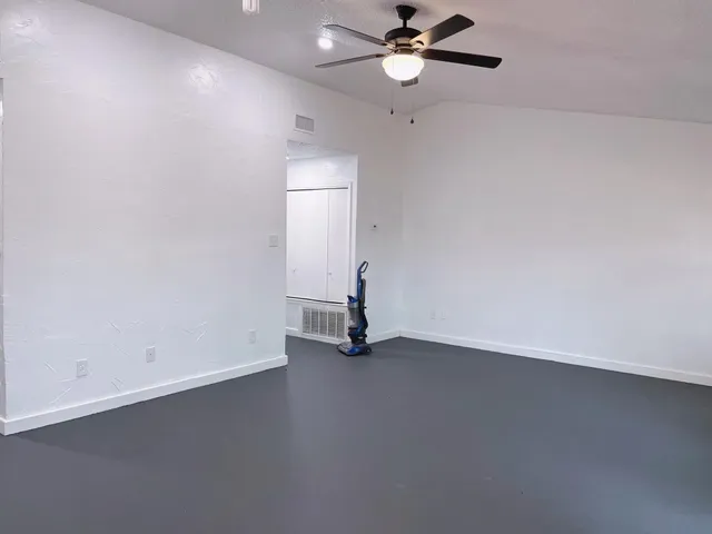 an empty room with a window and a ceiling fan