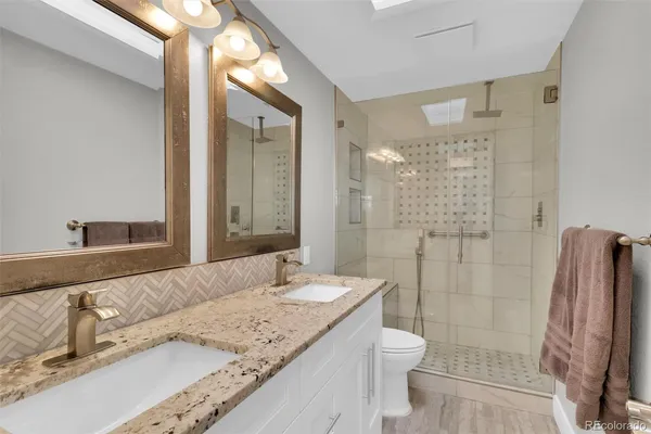 a bathroom with a granite countertop sink toilet and shower